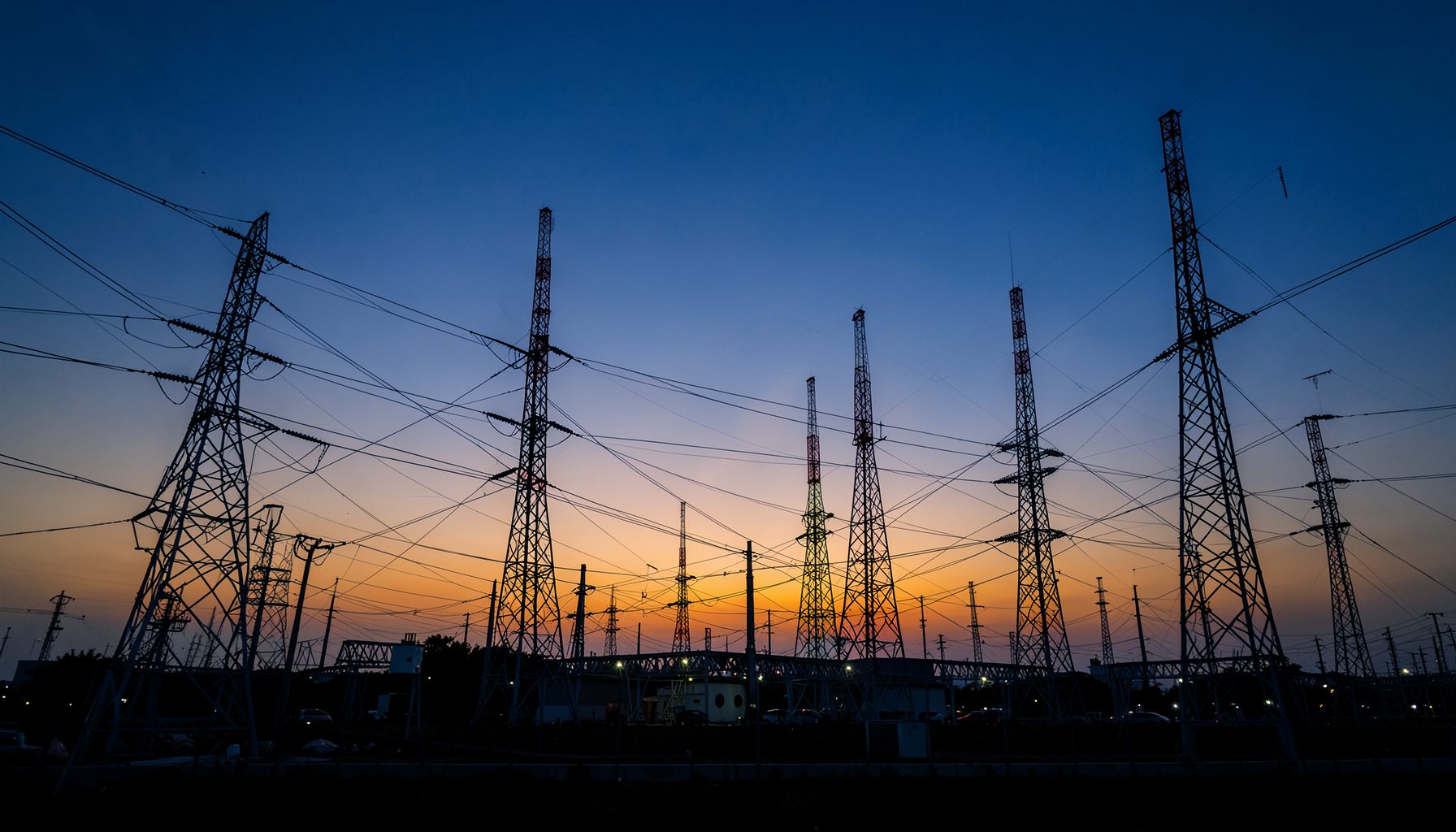 A wide-angle view of modern telecommunications infrastructure at dusk, with network towers silhouetted against a deep blue and amber sky, conveying connectivity and development across the Asia-Pacific region.