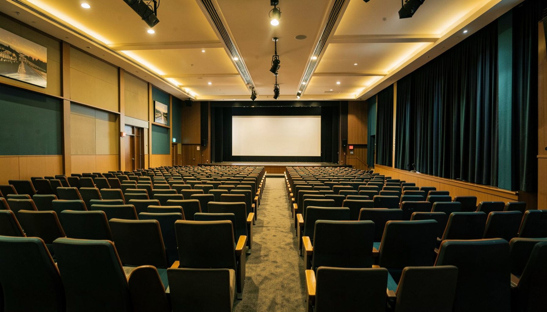 A wide conference hall with rows of seating and a stage, warm golden and teal tones, professional atmosphere